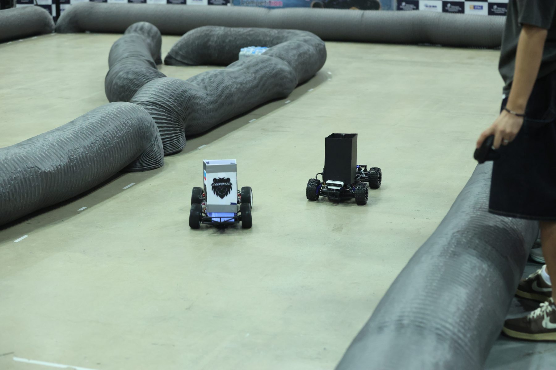The white-bodied DeepSpeed car alongside SNU ZERO's black-bodied car during a head-to-head race