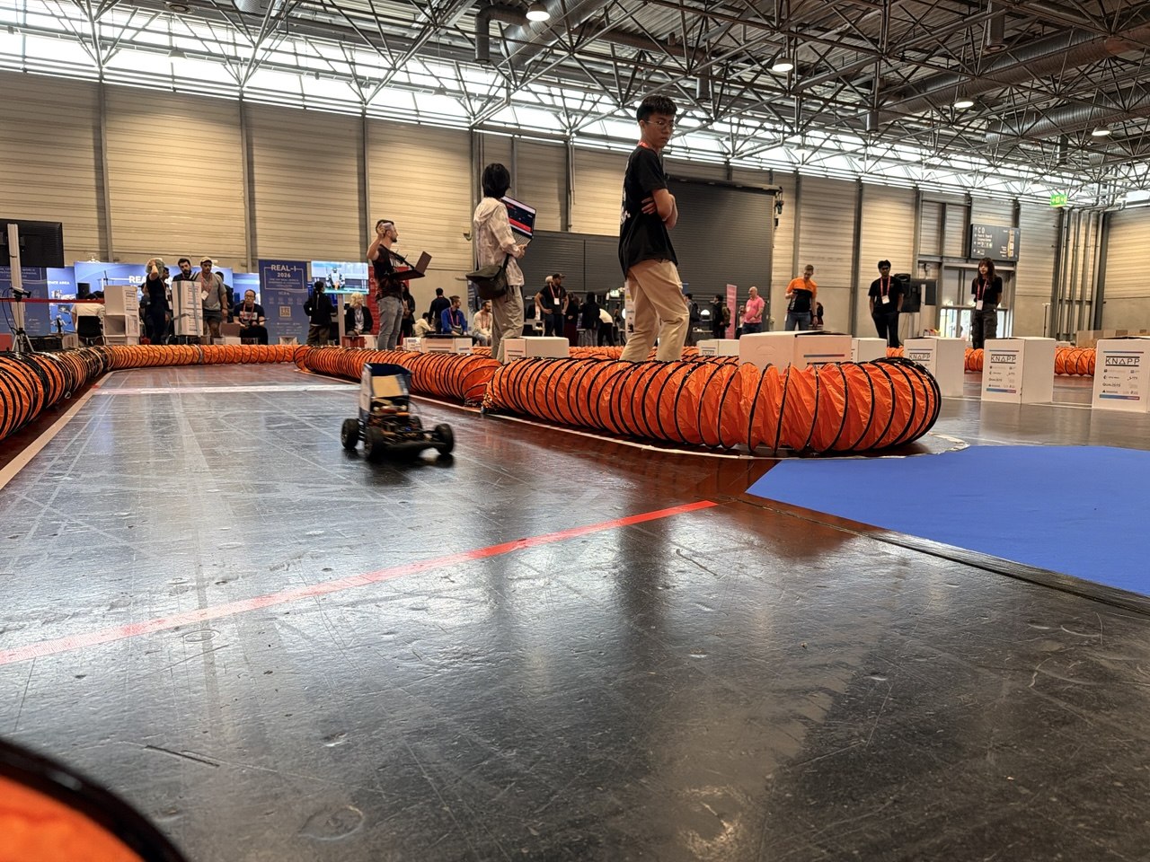 The car mid-run on the physical track, lined with orange barriers